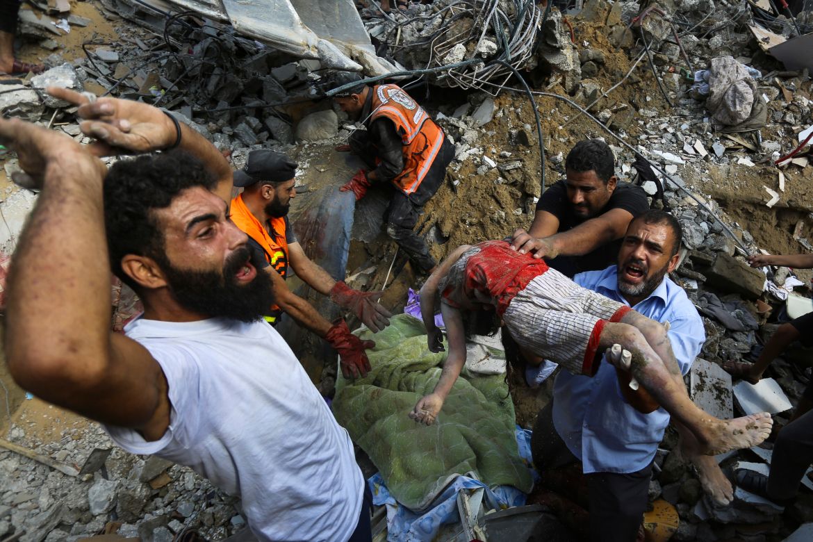 Palestinians carry a body of a dead child who was found under the rubble of a destroyed house after Israeli airstrikes on Gaza City