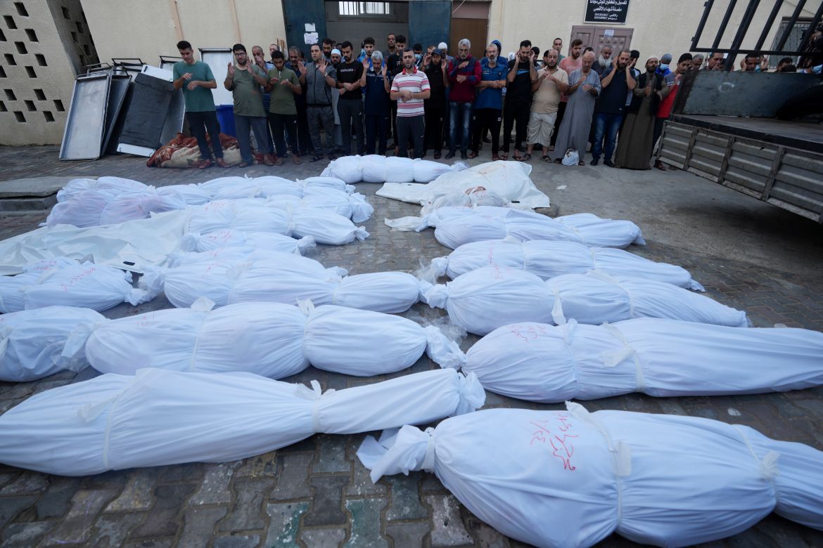 Palestinians pray by the bodies of people killed in the Israeli bombardment of the Gaza Strip in front of the morgue in Deir Al-Balah, Tuesday, Oct. 24