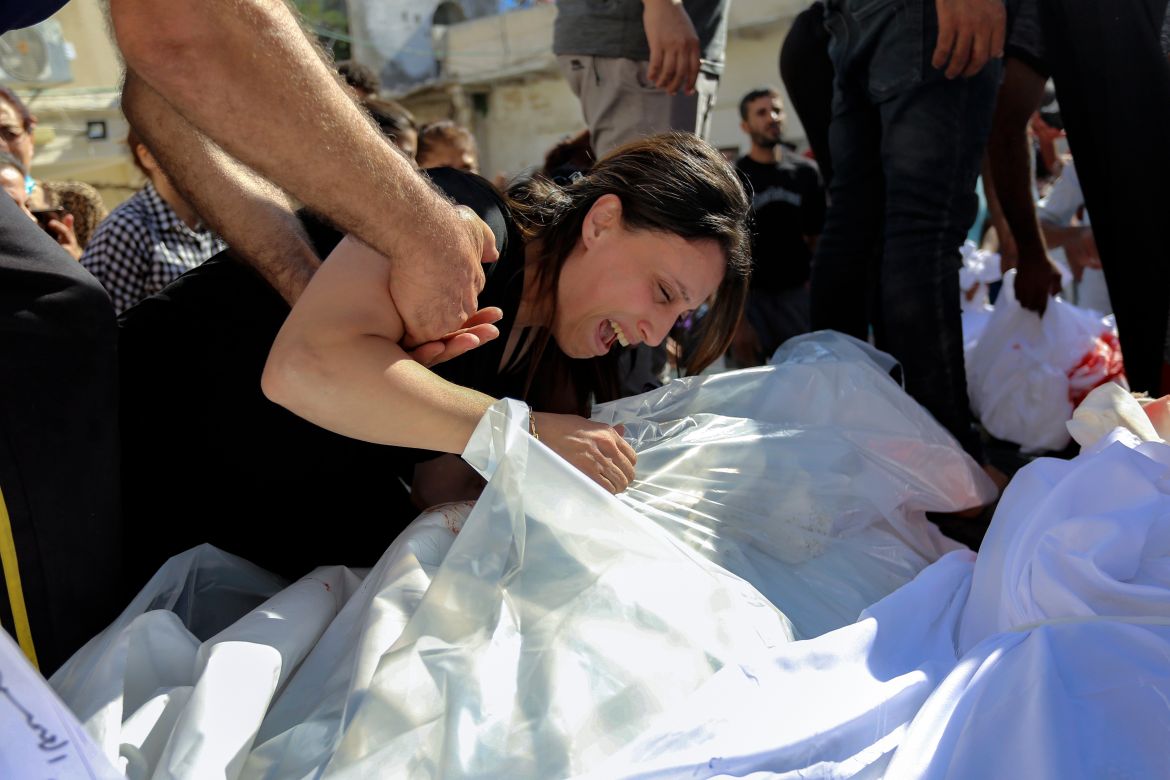 A Palestinian woman mourns over the bodies of her relatives who were killed in Israeli airstrikes that hit a Greek Orthodox church, in Gaza City, Friday