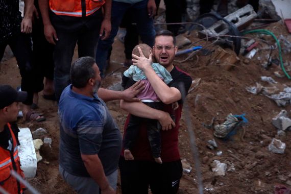 Un uomo palestinese piange mentre tiene in braccio un bambino morto che è stato trovato sotto le macerie di un edificio distrutto in seguito agli attacchi aerei israeliani nel campo profughi di Nusseirat, nel centro della Striscia di Gaza, martedì 31 ottobre 2023. (AP Photo/Mohammed Dahman)