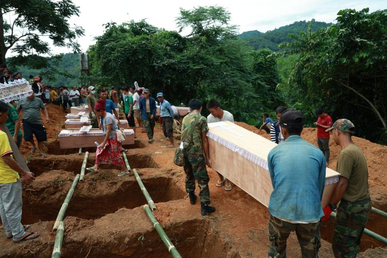 Kachin people hold a joint funeral for those killed in a military air rad on October 9. A rgoup of men are carrying a coffin towards a row of graves. Bamboo poles have been placed across each hole.