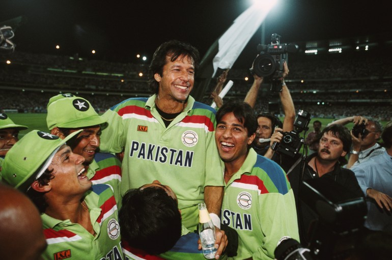 Pakistan cricket team carry captain Imran Khan as they celebrate their world cup win. Team is wearing green kits, photographers try to cpature the moment