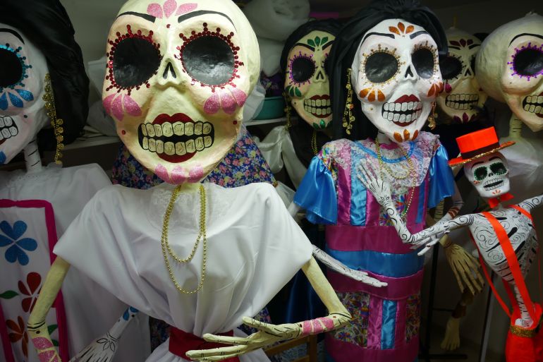 Dolls representing La Calavera Catrina — a brightly decorated skull — stand packed together.