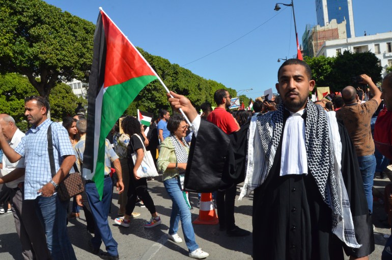 Youssef Khrairef, a lawyer dressed in heavy black robes with a white frill at the collar, waves a Palestinian flag on the streets of Tunis.
