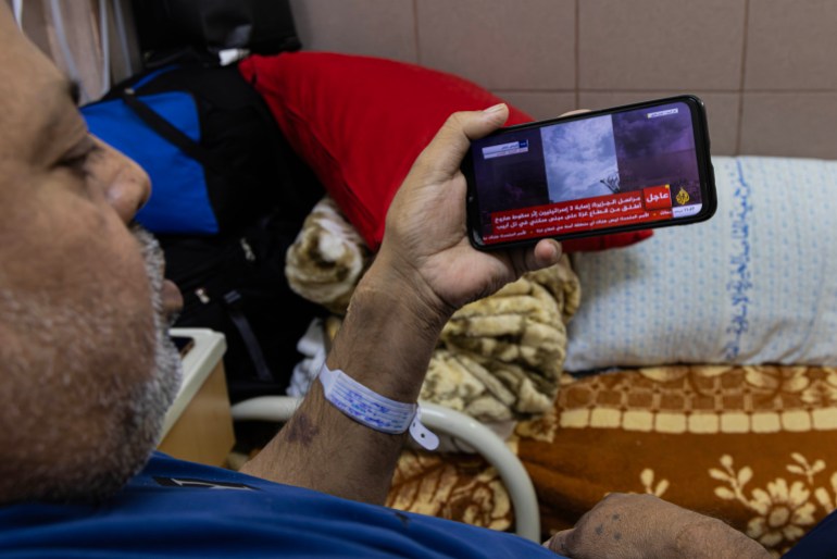 Nafez Al-Qahwaji acompanha as notícias de Gaza pelo telefone através de canais de TV na Internet 