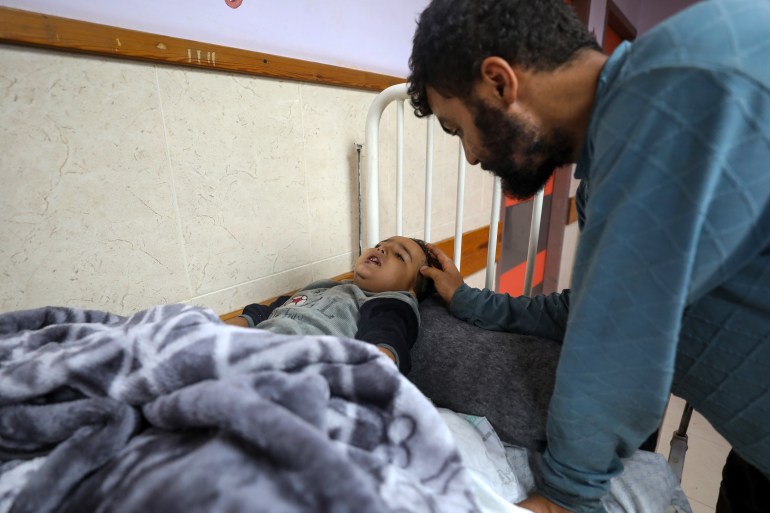 Ibrahim Abu Amsheh tends to his nephew Ahmad at the Al-Aqsa Martyrs Hospital in Deir al-Balah