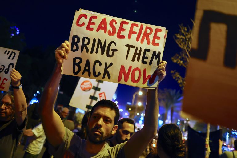 People hold placards as left wing supporters call for a ceasefire to allow negotiations following the escalation of the Israel-Hamas conflict, during a rally in Tel Aviv
