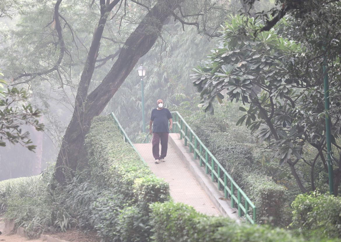 An Indian man wearing a face mask walks as the city is engulfed in heavy smog at Lodhi garden, in New Delhi, India, 04 November