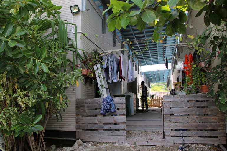 A view of the exterior of an offshore detention camp in Nauru. The buildings are close together. There are clothes hanging. Also some bushes