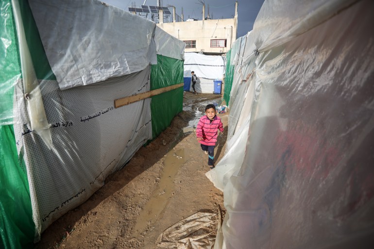A child runs between the tents set up for displaced Palestinians on the grounds of Al-Aqsa Martyrs Hospital in Deir al-Balah in central Gaza Strip 