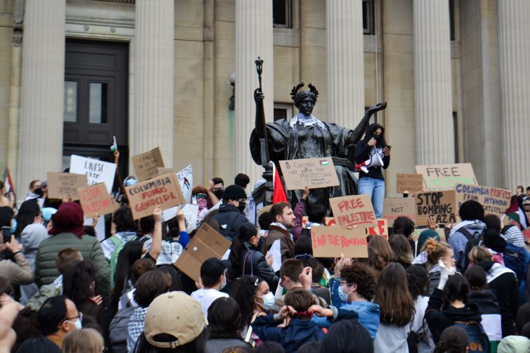Students rally in front of a bronze statue of a seated woman with a crown of laurel leaves and a staff, to show support for Palestinian rights on Columbia University's campus.