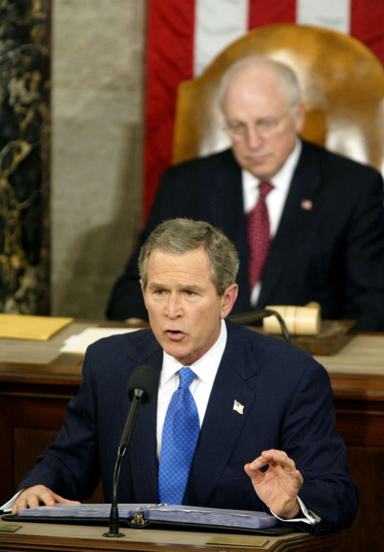 George W. Bush, dressed in a dark suit and blue tie, takes to a podium at Congress to deliver his State of the Union address in 2003. His vice president, Dick Cheney, sits behind him.