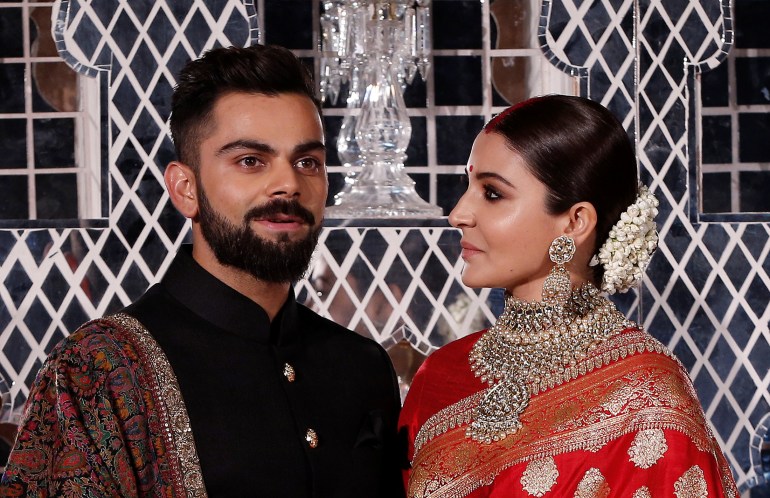 India's cricket team captain Virat Kohli (L) and his wife, Bollywood actress Anushka Sharma, pose during a photo opportunity at their wedding reception