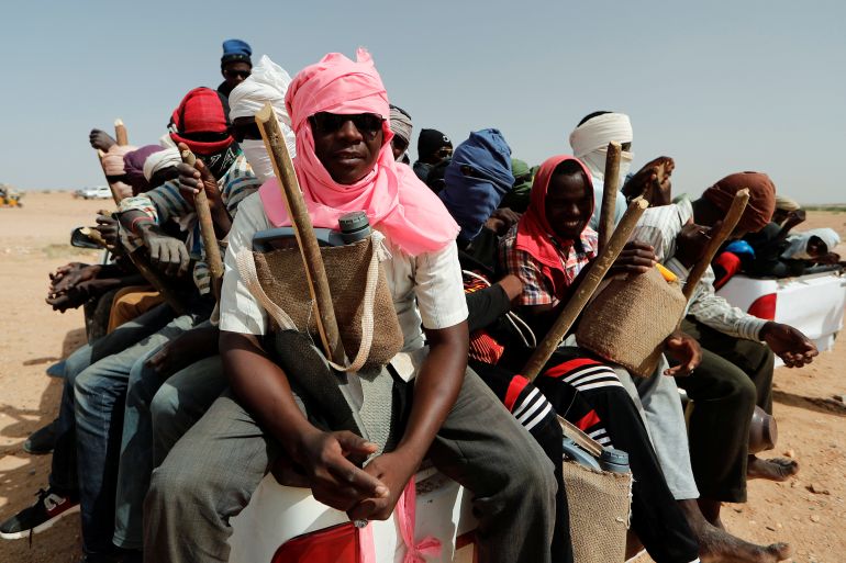 Nigeriens sit in the back of a truck, preparing to travel north towards Libya