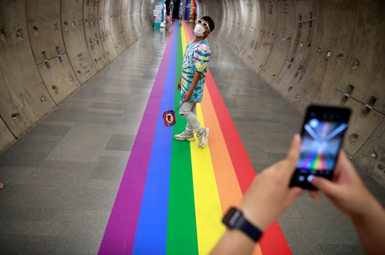 LGBT couple take photos of each other on a rainbow flag-themed path during pride month at Samyan MRT station in Bangkok, Thailand June 4, 2021. REUTERS/Soe Zeya Tun