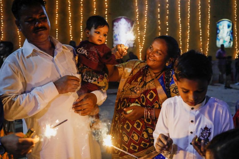 Sawantri, 40 anos, ajuda seu filho a agitar uma faísca acesa durante o Diwali, o festival hindu das luzes, em Karachi, Paquistão.