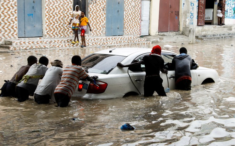 People push a vehicle along a flooded street in Mogadishu, Somalia April 28, 2023. REUTERS/Feisal Omar