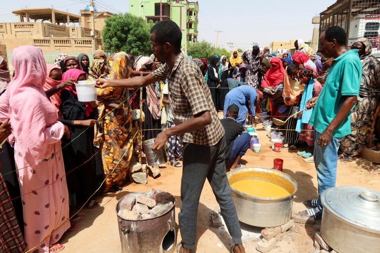A volunteer distributes food to people in Omdurman, Sudan,