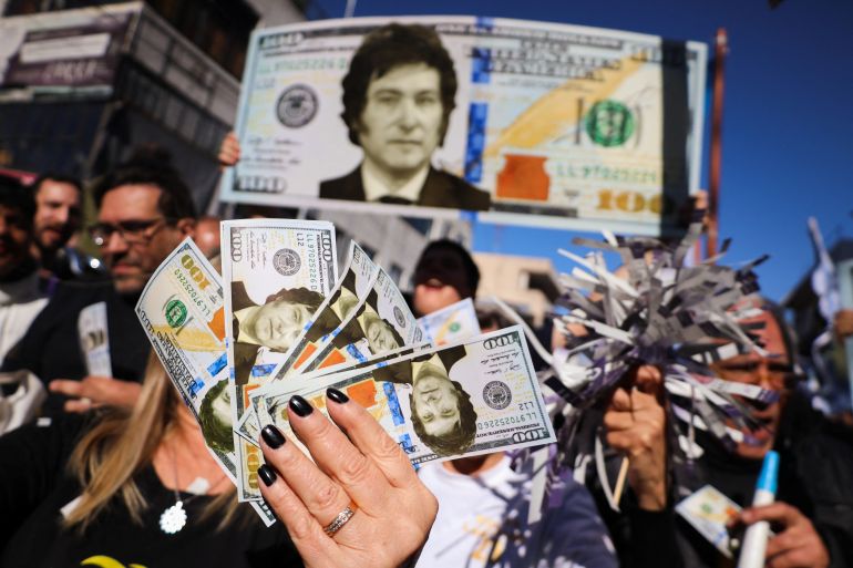 Supporters of Argentine presidential candidate Javier Milei hold dollar bills with his face on them,