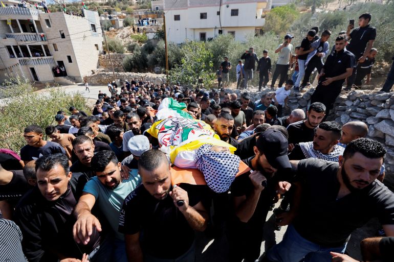 Mourners carry the body of a young boy