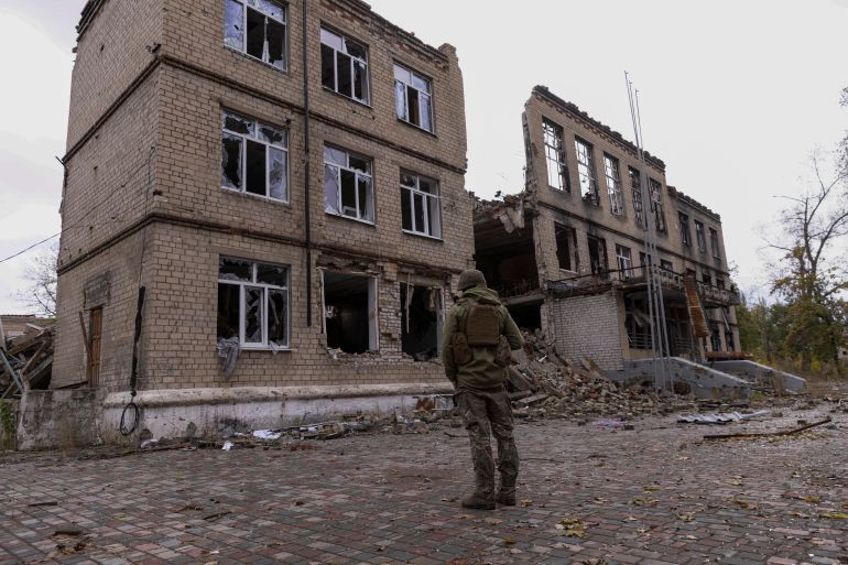 A police officer stands in front of a damaged building in the town of Avdiivka, Ukraine
