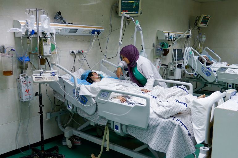 A medical worker assists a Palestinian, who was wounded in Israeli strikes, at the Intensive Care Unit (ICU) of Nasser hospital