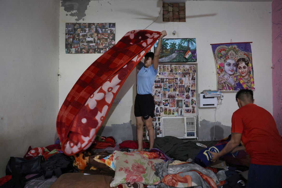 Chavi, 13, folds a blanket in her room, at the Altius wrestling school's boarding hostel in Sisai, Haryana, India.