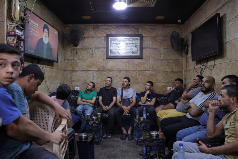 La gente osserva il segretario generale di Hezbollah, Hassan Nasrallah