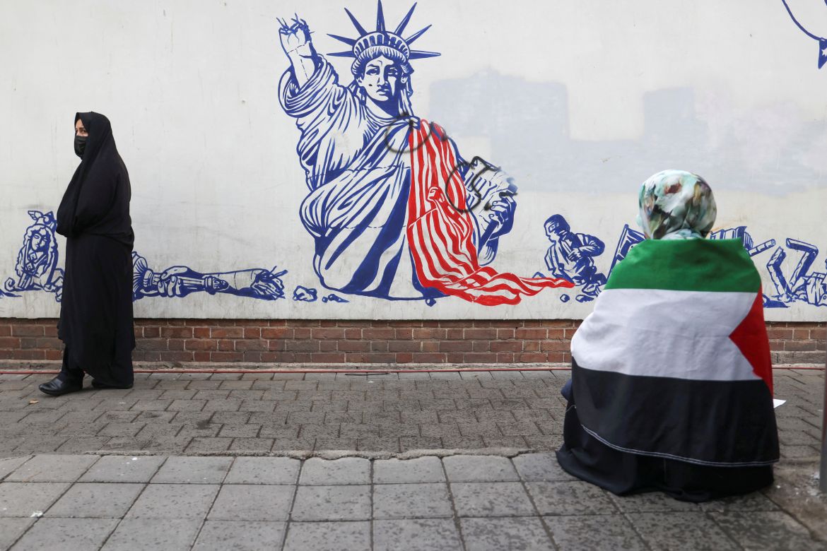 An Iranian woman walks past an anti-U.S. mural on the wall of former U.S. Embassy during the 44th anniversary of the U.S. expulsion from Iran, in Tehran.