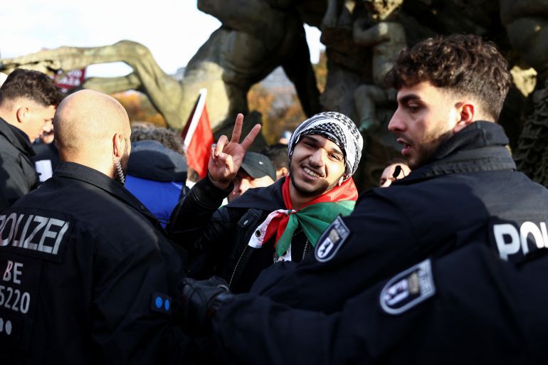 A protester gestures as he is detained by police officers after climbing Neptune Fountain during a pro-Palestinian demonstration, amid the ongoing conflict between Israel and Palestinian Islamist group Hamas, in Berlin, Germany, November 4, 2023. REUTERS/Liesa Johannssen