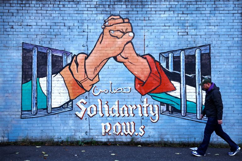 A man walks past a mural in solidarity with Palestinians in Gaza, amid the ongoing conflict between Israel and Hamas, in the Nationalist area along the International Wall on the Falls Road in Belfast, Northern Ireland, November 4, 2023. REUTERS/Clodagh Kilcoyne