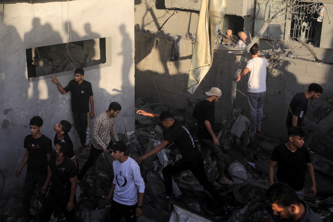 Palestinians search for casualties at the site of Israeli strikes on houses, amid the ongoing conflict between Israel and Palestinian Islamist group Hamas, in Maghazi refugee camp in the central Gaza Strip