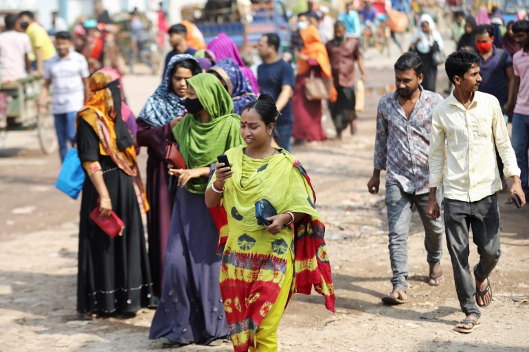 A female garment worker uses cellphone while coming out of a factory during lunch hours at the Ashulia area, outskirts of Dhaka, Bangladesh