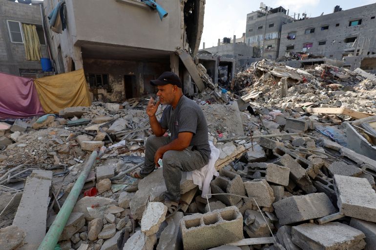 A Palestinian man of Kullab family, who resides on his home that was damaged in an Israeli strike, sits on the rubble, in Khan Younis