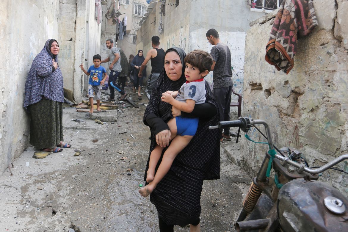 A woman holds a child as Palestinians are evacuated at the site of an Israeli strike on a house, in Rafah