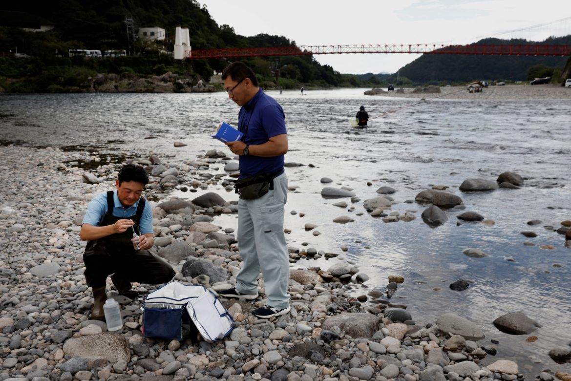 Gifu University's professors Morihiro Harada (right) and Shigeya Nagayama collect water to analyze the environmental DNA of ayu river fish from the Nagara River in Mino, Seiki, Japan.