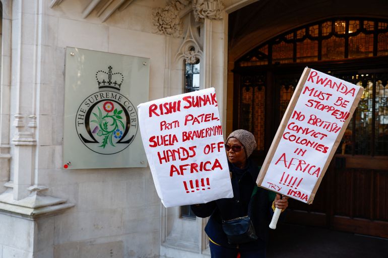 A protestor holds placards outside of the Supreme Court, following its ruling on whether the government can go ahead with its plan to deport migrants to Rwanda, in London, Britain, November 15, 2023. REUTERS/Peter Nicholls