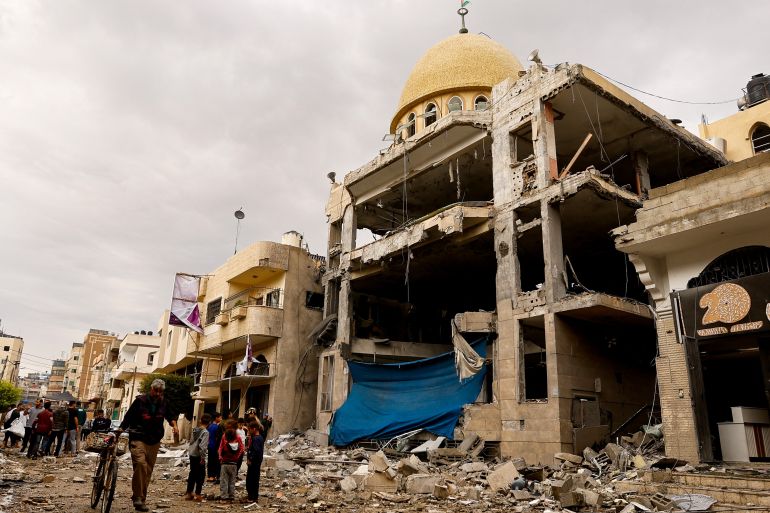 Palestinians stand next to a mosque destroyed in an Israeli air strike