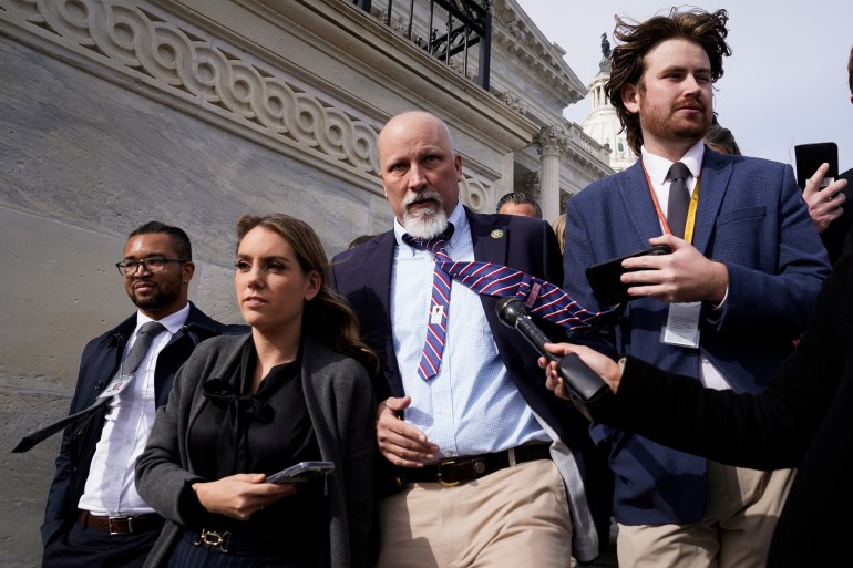 Chip Roy przechodzi przez zatłoczoną grupę reporterów schodząc po schodach Kapitolu, a jego krawat w paski trzepocze na wietrze.