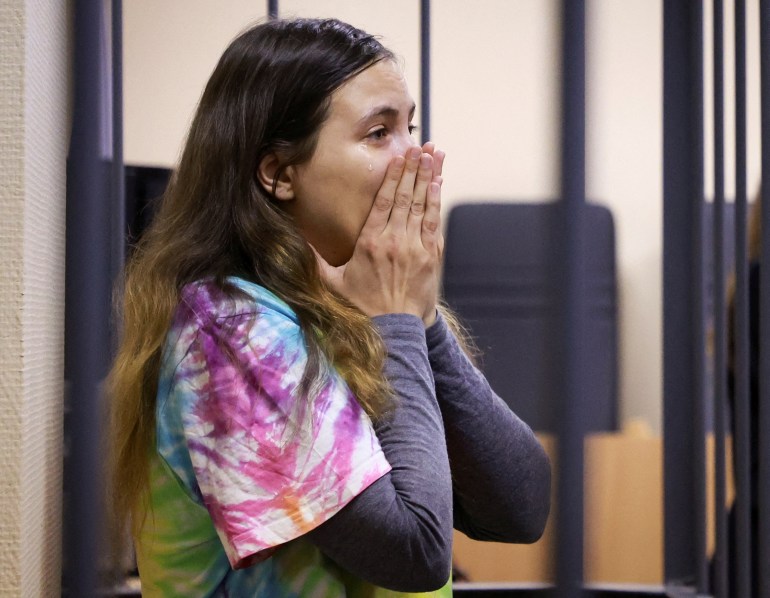Alexandra (Sasha) Skochilenko reacts to her sentencing. She is standing in the dock and has her hands to her face in shock.
