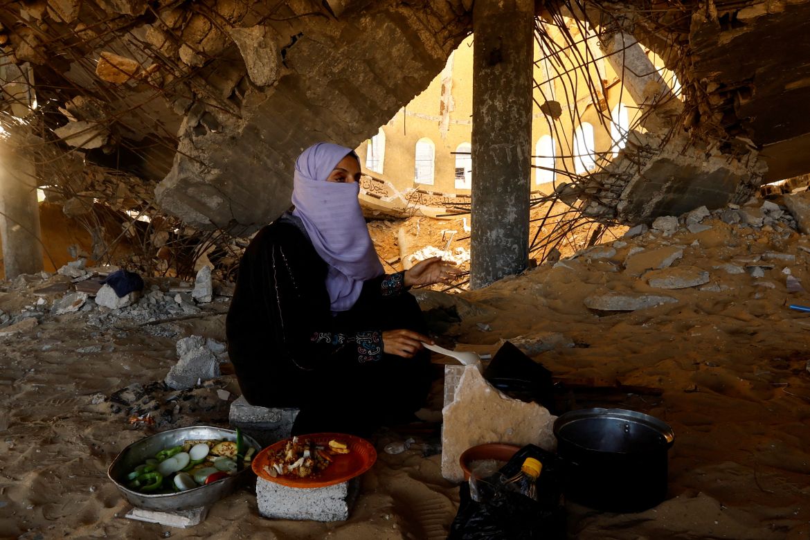 A woman cooks in a destroyed mosque, amid shortages of food supplies and fuel, as the conflict between Israel and Palestinian Islamist group Hamas continues, in Khan Younis in the southern Gaza Strip