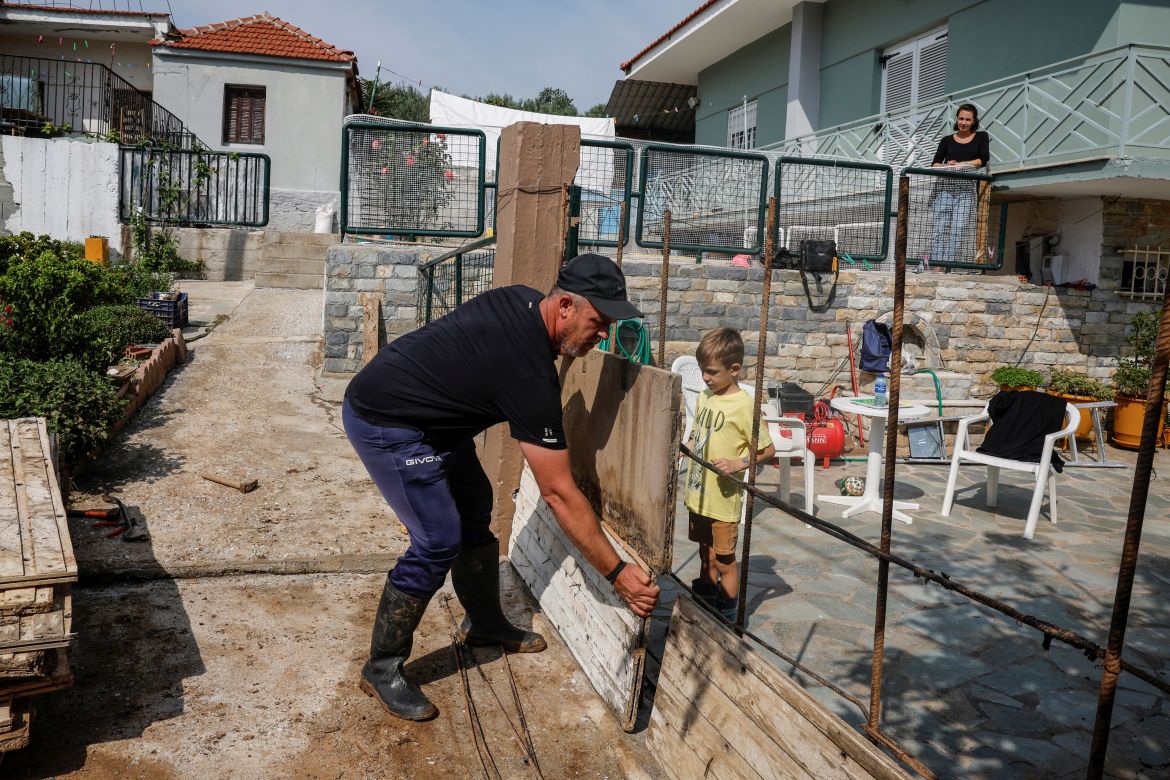 Vasilis Tsiamitas, 46, prepares wooden panels to construct a cement wall in front of his house to prevent further flooding, as his son Christos, 5, and his wife Christina Gkareli, 33, look on, in the village of Sesklo, Greece.