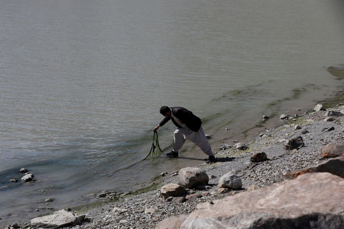 Muhammad Yasin, 35, an environmental sciences graduate researcher, lifts algae from the surface of stagnant water at the Gamoo Bhr glacial lake near the Darkut glacier in Darkut village, Yasin valley, in the Gilgit-Baltistan region of Pakistan.