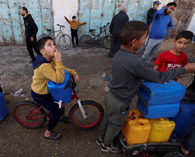 Palestinians children wait in a line with containers to collect water, amid drinking water shortages, in Rafah in the southern Gaza Strip, November 23, 2023. REUTERS/Ibraheem Abu Mustafa