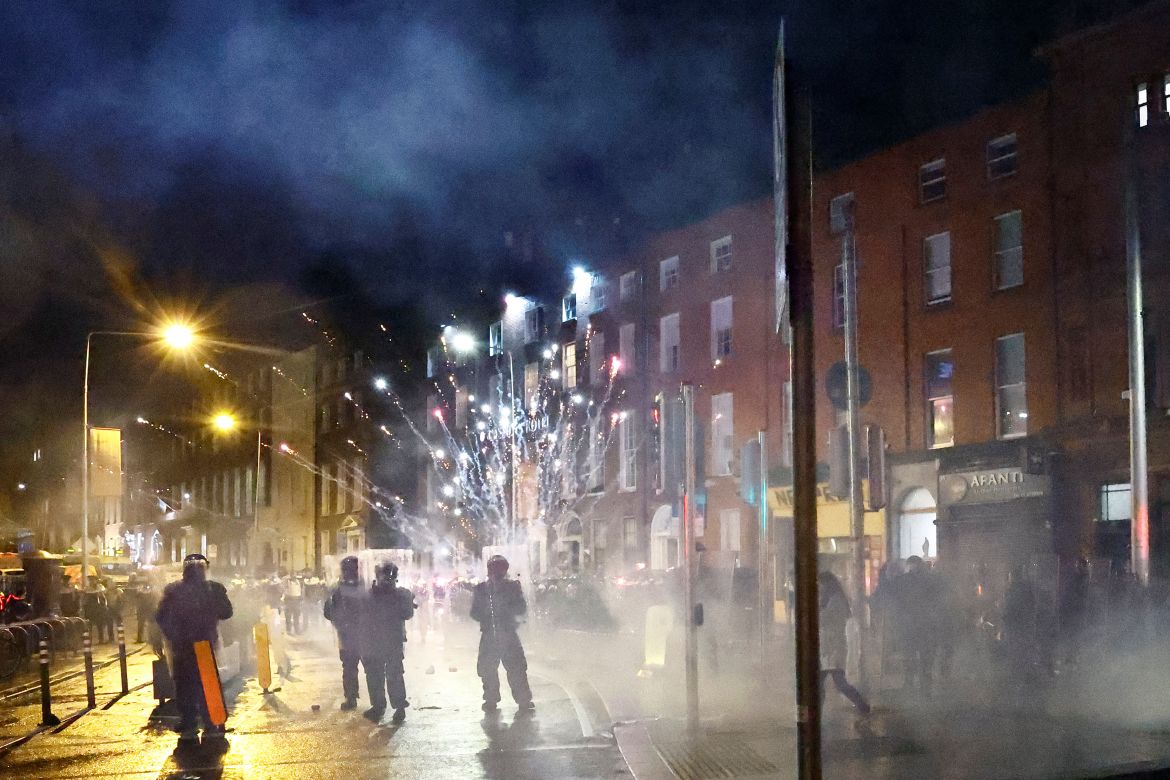 Fireworks are thrown at police officers as a riot breaks out