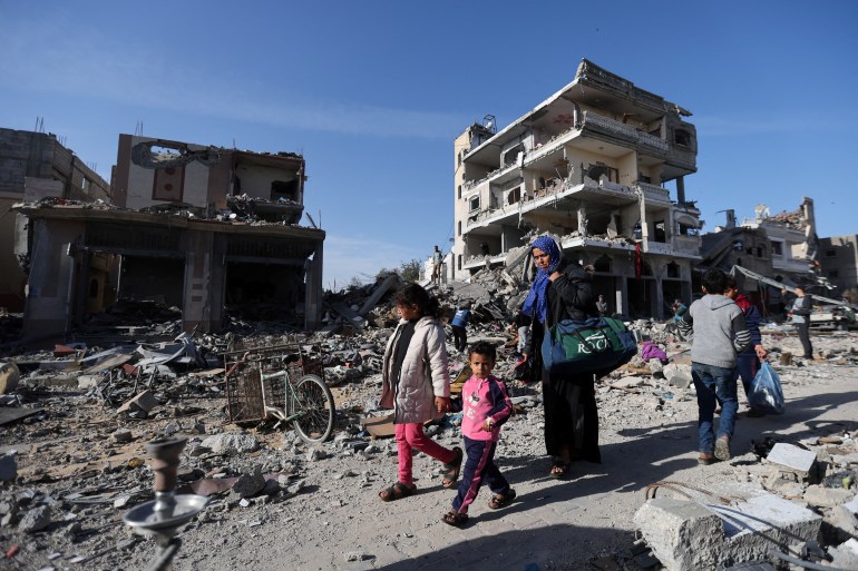 Displaced Palestinians return to their homes as they walk near houses destroyed in an Israeli strike during the conflict,