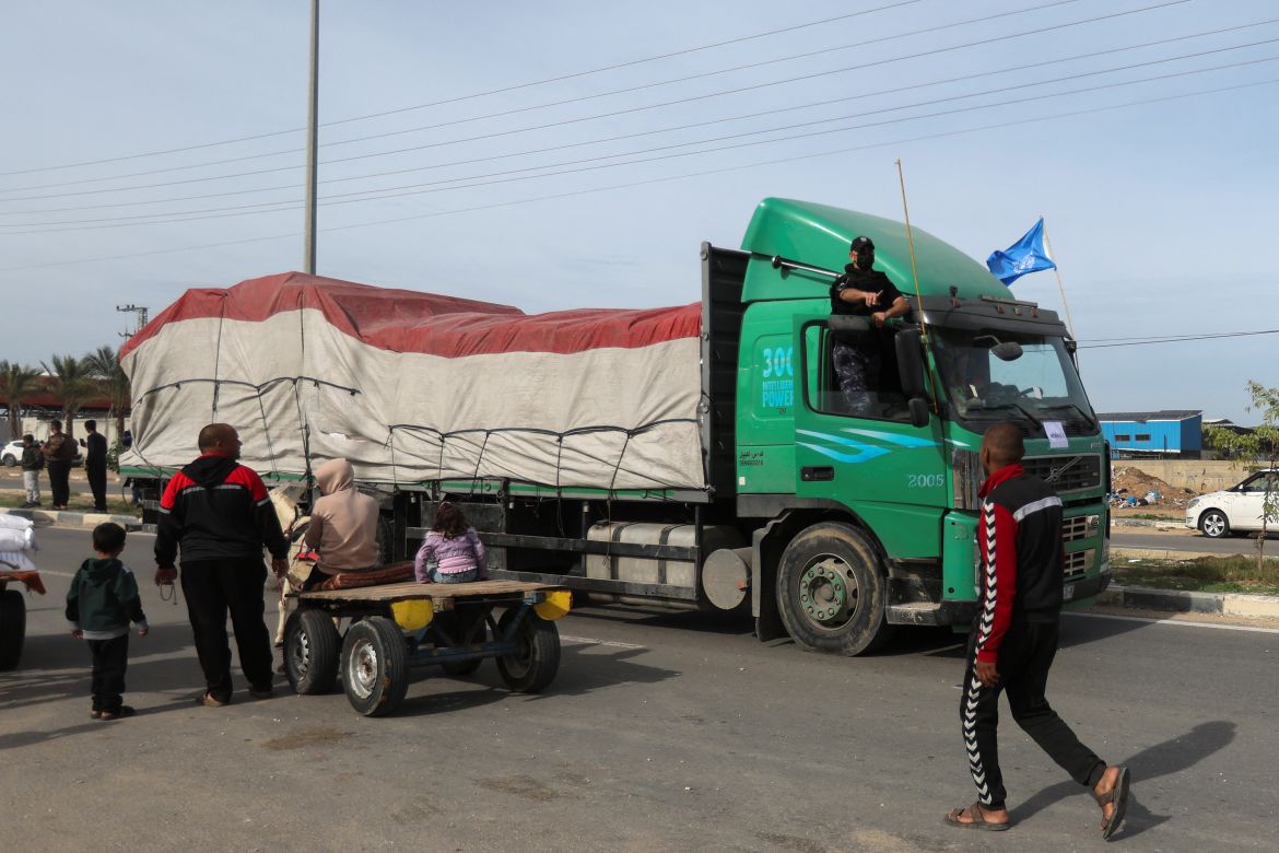 Aid trucks move on a road as Palestinians look on, during a temporary truce between Hamas and Israel, in Rafah, in the southern Gaza Strip November 25