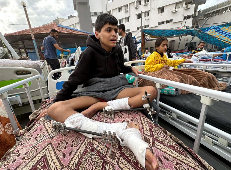 Palestinians wounded in Israeli strikes during the conflict sit on beds at Al Shifa hospital which was raided by Israeli forces during Israel's ground operation, amid a temporary truce between Israel and Hamas in Gaza City