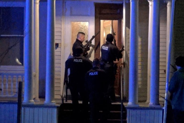 Police search a house in the neighbourhood after a gunman shot and wounded three college students of Palestinian descent in Burlington