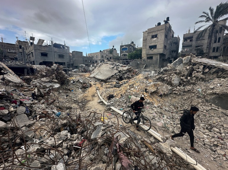 I palestinesi camminano tra le macerie, mentre ispezionano le case distrutte dagli attacchi israeliani durante il conflitto, nel mezzo della tregua temporanea tra Hamas e Israele, nel campo profughi di Khan Younis, nella striscia di Gaza meridionale, il 27 novembre 2023. REUTERS/Mohammed Salem